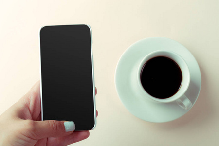 女性手和咖啡桌上的智能手机