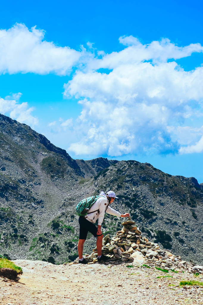 一个年轻人徒步旅行到达山顶大厦岩石金字塔美丽的高山风景夏天