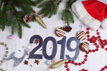 图 2019, 饼干和圣诞装饰品, 圣诞树上有一个红色的帽子在一个浅色的背景。新年概念。问候圣诞贺卡。平躺