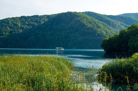 美丽的湖与小船在蓝色水在绿色小山之间, 国家公园普利特维采湖, 克罗地亚, 欧洲