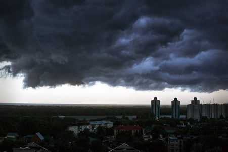 在城市雨季城市景观日落背景下, 天空中的乌云笼罩在房屋和建筑物之上