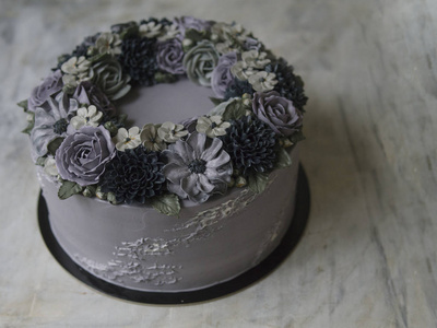 灰色奶油蛋糕装饰着黑暗的奶油花在质朴的背景.