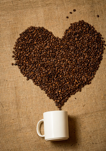 咖啡豆从躺在画布上的白色杯子的心