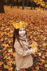 画像独自可爱的女孩与冠叶子在秋天公园
