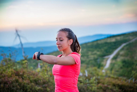 在山上跑步的时候, 女人在她的运动手表上检查时间。Szczyrk, Beskidy 山, 西里西亚 Beskid, 波兰