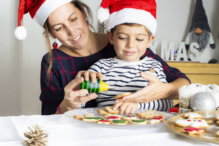 母亲和儿子在家里装饰圣诞饼干