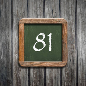 数字81在绿色黑板在木背景之上照片