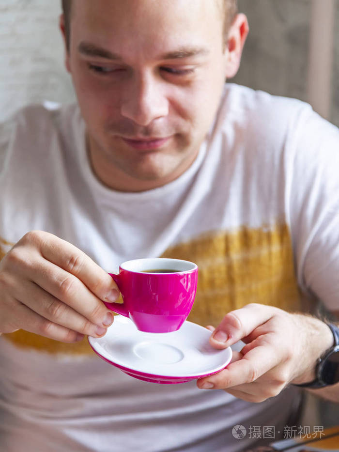 那个年轻人手里拿着一杯咖啡.专注于杯子