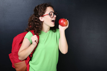 小女孩与背包和苹果在黑板背景