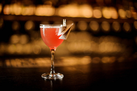 一杯美味的红色鸡尾酒, 装饰有一架纸飞机站在酒吧柜台上照片
