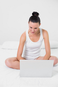 休闲的年轻女子在床上使用笔记本电脑