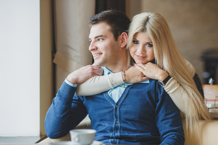 快乐的年轻夫妇互相拥抱和在一家咖啡馆里喝咖啡的肖像