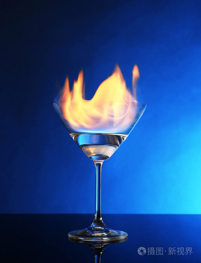 燃烧酒精在蓝色背景上的玻璃