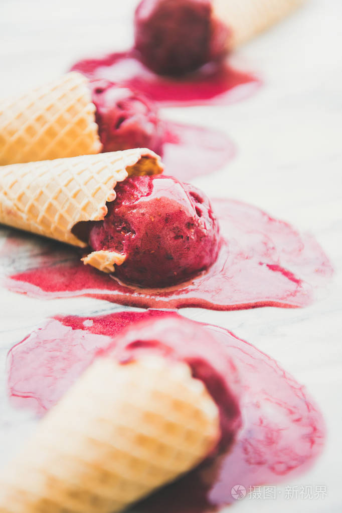 融化天然覆盆子冰淇凌冰淇淋勺在甜华夫饼锥以上大理石背景