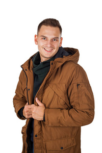 英俊的年轻人穿着浅棕色的冬季帕卡夹克微笑对照相机在被隔绝的背景