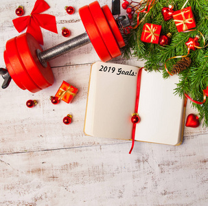 圣诞节背景与日记, 哑铃, 红色礼品盒, 杉木树枝上的白色木背景, 复制空间。平躺, 顶部视图。规划理念
