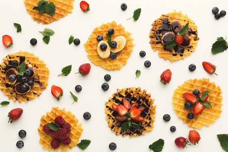 比利时薄饼与果子和焦糖在白色背景。香蕉, 蓝莓和草莓的格子饼干的分类。美食和美味的早餐概念, 顶部视图