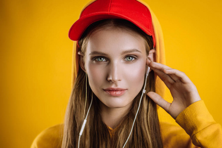 美丽的女孩听音乐的耳机, 照片在工作室的黄色背景