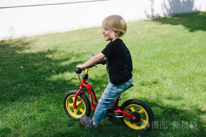 3岁快乐幼儿男孩骑红色自行车。小孩学会了骑自行车。运动自行车主动玩耍和童年概念