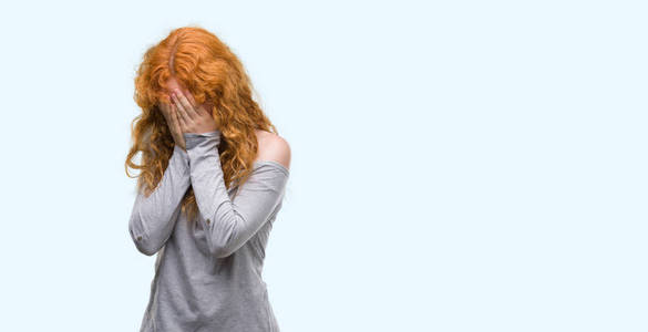 年轻的红发女人带着悲伤的表情捂着脸用手哭着.抑郁症概念照片
