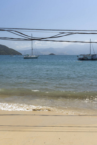 美丽的热带海滩景观与绿色的水, 蓝天和丑陋的电缆在伊尔哈格兰德, 科斯塔韦德, 南里约热内卢, 巴西