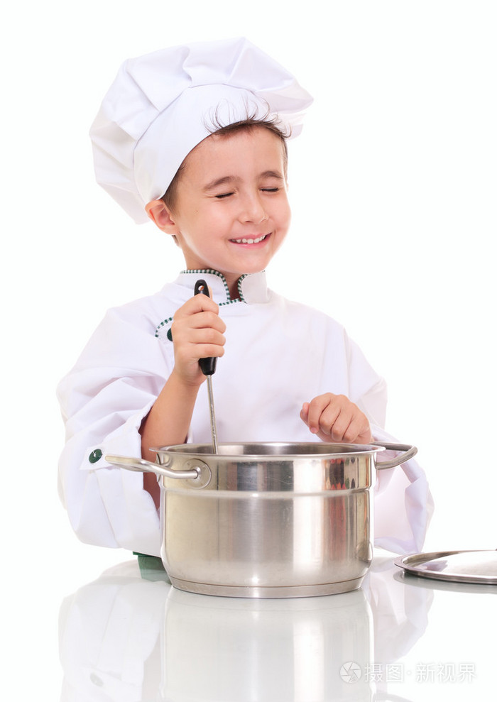 用勺子搅拌锅的小快乐的男孩厨师.