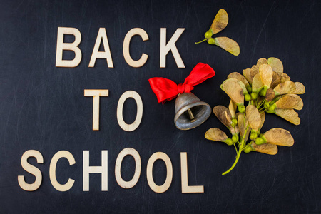 回到学校的概念。上图横幅学校响铃和秋天干燥叶子在教室黑板背景