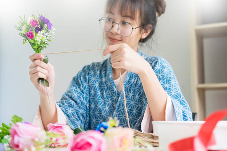 年轻女性企业所有者花店制作或安排人造花背心在她的商店, 工艺和手工制作的概念