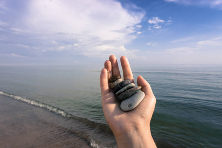 在夏季浪潮中, 一只手捧着许多石头在波罗的海沿岸。