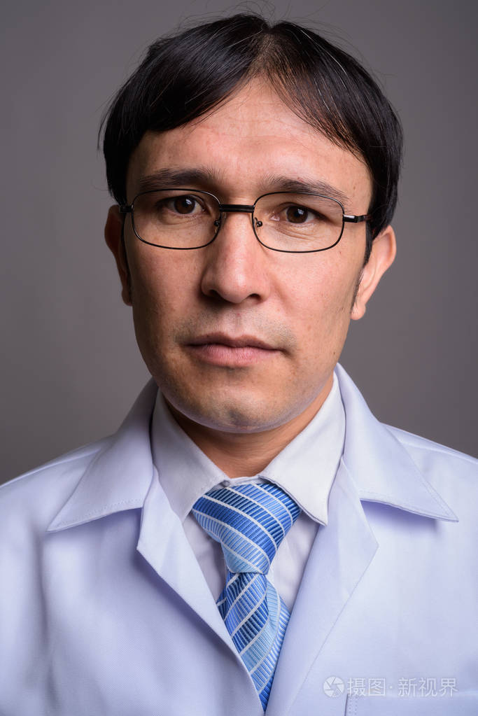 年轻的亚洲男子医生在灰色背景下戴眼镜的工作室镜头