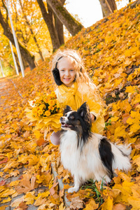 小美丽的女孩与金发和小狗在秋季背景