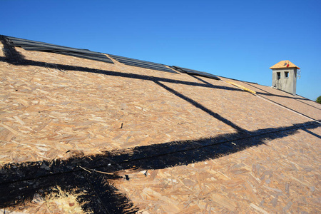 屋面施工。屋面准备沥青瓦安装在房屋建筑木制屋顶与沥青喷雾。屋面施工。安装沥青屋面瓦片