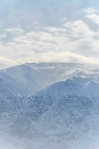 冬天的山。雪覆盖的山。冬季景观。冬日的阳光明媚的一天在山麓。雪山上的云