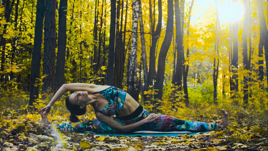 在秋季森林做舞蹈运动的年轻美丽的妇女