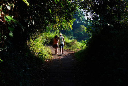 两个年轻的旅行者走在一起沿着小路漫步, 同时享受美丽的自然景观在夏季。在亚洲度假期间, 一些游客在户外度过休闲时光