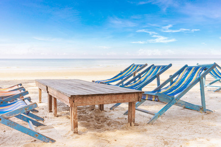 在假期暑假放松的时候, 在海滩上拥有明亮的蓝天的躺椅或 Liegestuhl