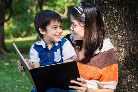 母亲与她的儿子，在公园的微笑脸读一本书