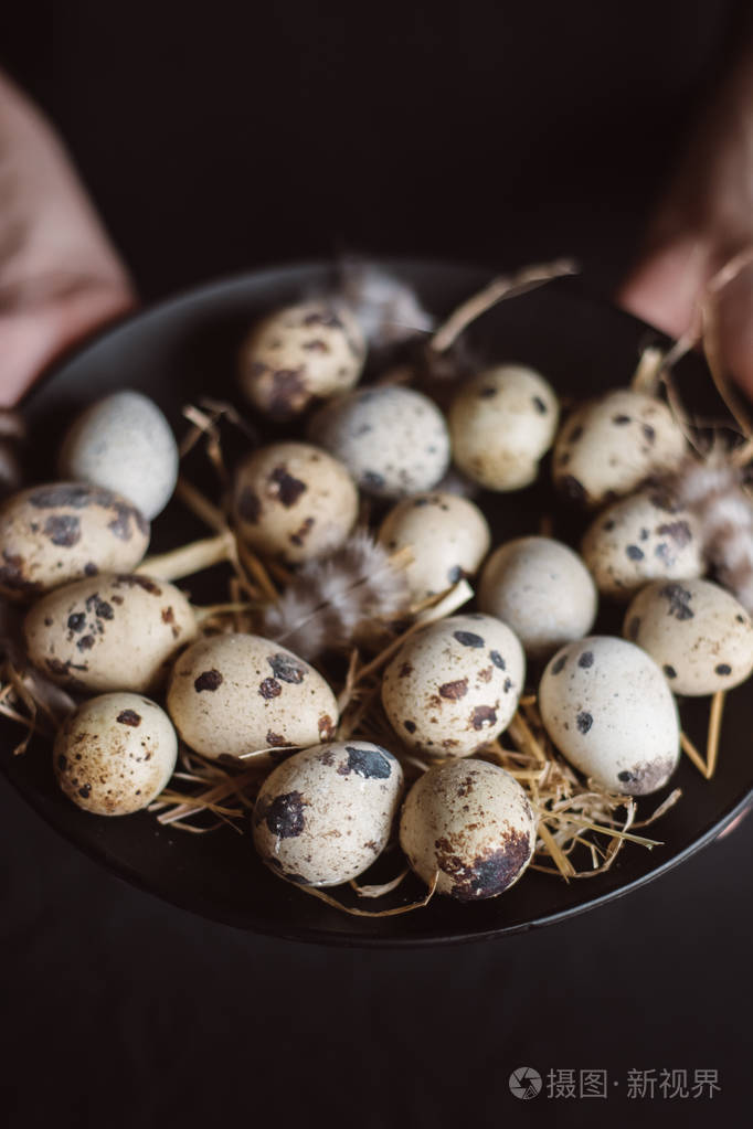 厨师把生鹌鹑蛋放在黑色盘子里
