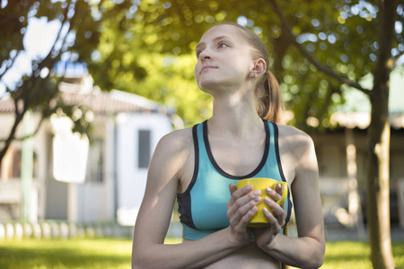 美丽的女人在 spor 顶着一杯茶。夏天早晨在庭院里