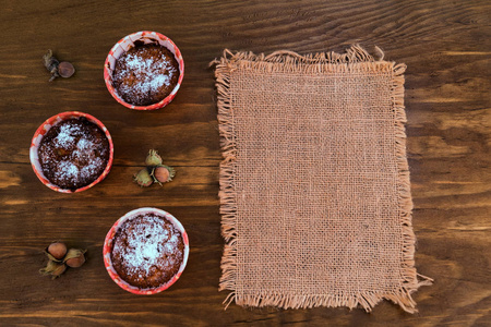 三燕麦片饼干洒上糖粉, 一些榛子坚果, 在木质背景上的布餐巾, 顶部视图, 文本空间