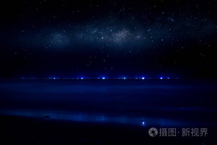 夜空中的星星在沙滩上, 小船上的蓝光在海面上