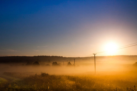 黎明时分, 清晨的太阳升起在田野和输电线路上, 云雾缭绕的景色, 电线创造线条