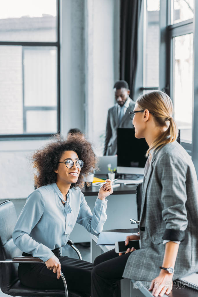 微笑的多文化女商人在办公室交谈