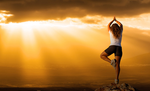 健康的女人练习瑜伽在日落时