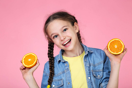 快乐女孩微笑和举行橙色水果在粉红色的背景