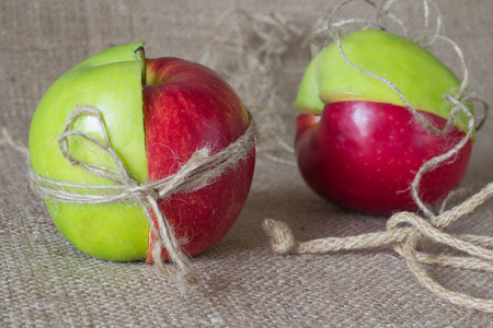 一半的绿色和红色的苹果被捆绑在解雇的背景下的绳子