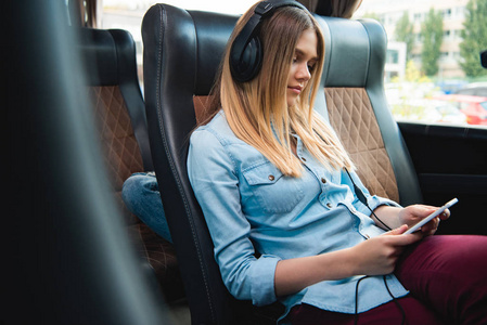妇女在耳机睡觉和听音乐与智能手机在旅途中的旅行巴士