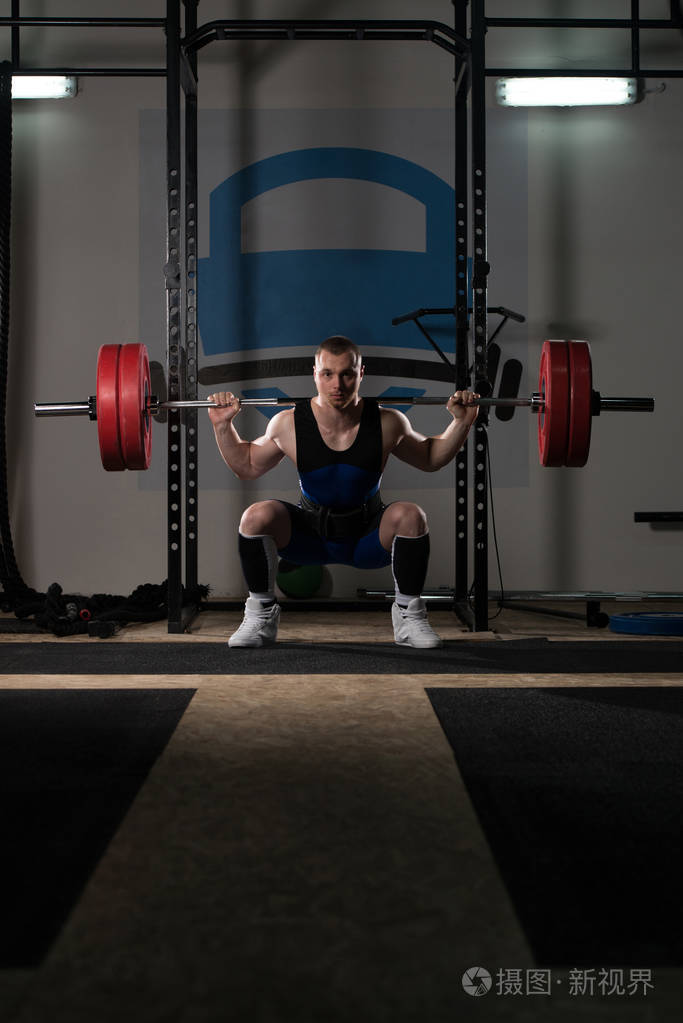 在健身房锻炼中举重运动员用杠铃锻炼腿