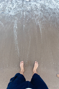 在沙子的蓝色波浪与男性脚