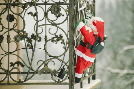 被白雪覆盖的圣诞老人爬上绳梯上的阳台。圣诞安装